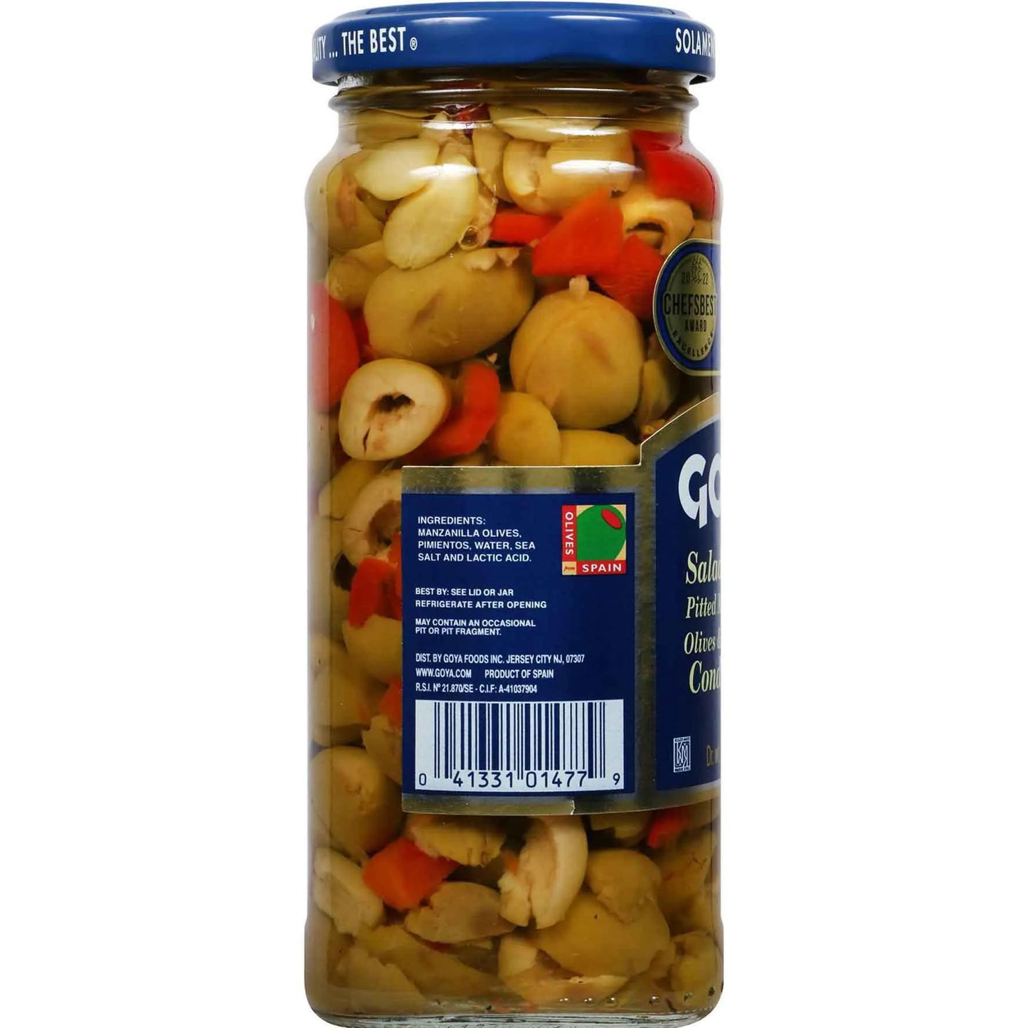 A glass jar of gourmet nuts and dried fruits, featuring cashews, olives, and red peppers in oil, sealed with a blue lid and a blue and white label.