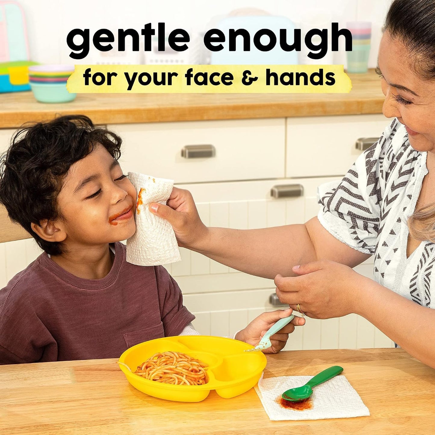 Woman cleaning a child's face with a napkin in a kitchen setting, with text 'gentle enough for your face & hands'.