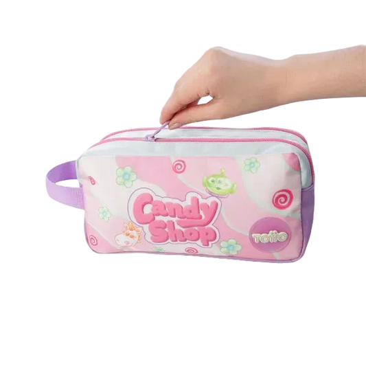 A pink and white zippered pencil case with a purple handle, decorated with 'Candy Shop' and 'relie' graphics, held by two hands against a white background.
