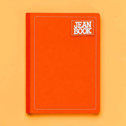 An orange hardcover notebook with white contrast stitching and a white patch label reading 'JEAN BOOK' in white text, shown on a solid orange background.