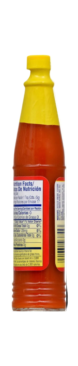 A close-up of a hot sauce bottle showing the nutrition facts label on the side. The bottle is filled with orange-red hot sauce, has a yellow cap, and a red-and-white label with black text.